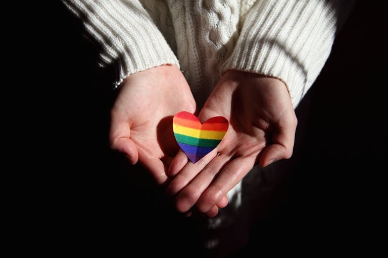 Hands offering a rainbow heart symbolizing love and LGBTQ+ pride.